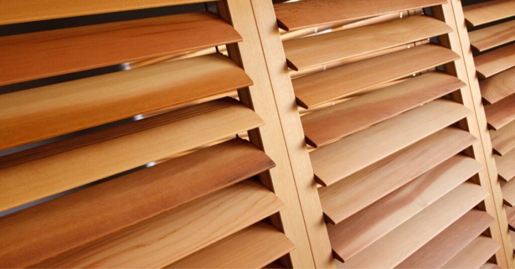 Close-up view of wooden window shutters with horizontal slats in varying shades of light brown.