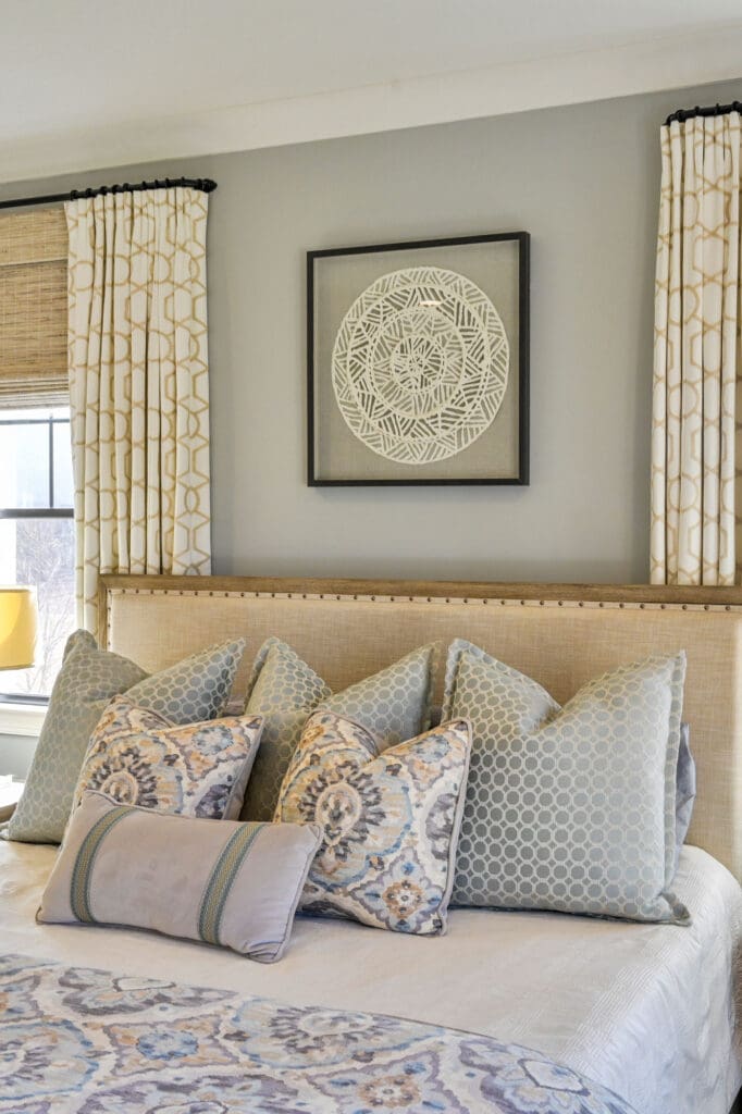 Custom bedding and layered drapery panels with woven wood shades in a Jamestown, NC bedroom.