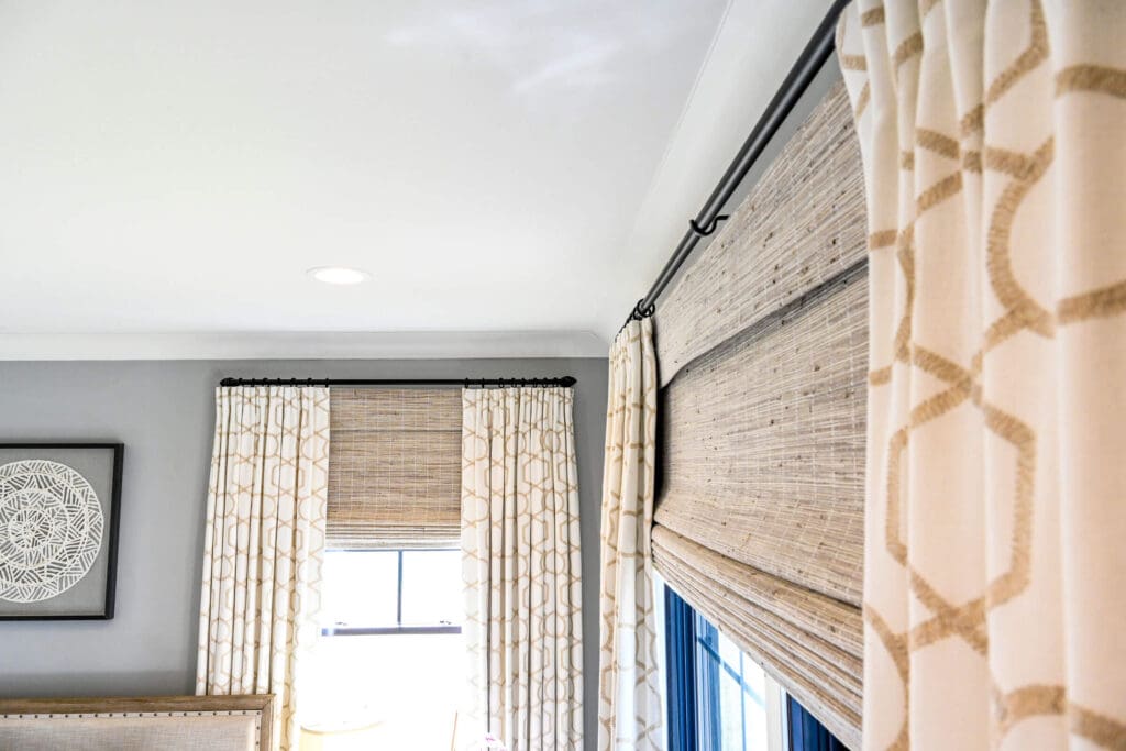 A close-up of custom woven wood shades and drapery panels in a bedroom in Jamestown, NC.