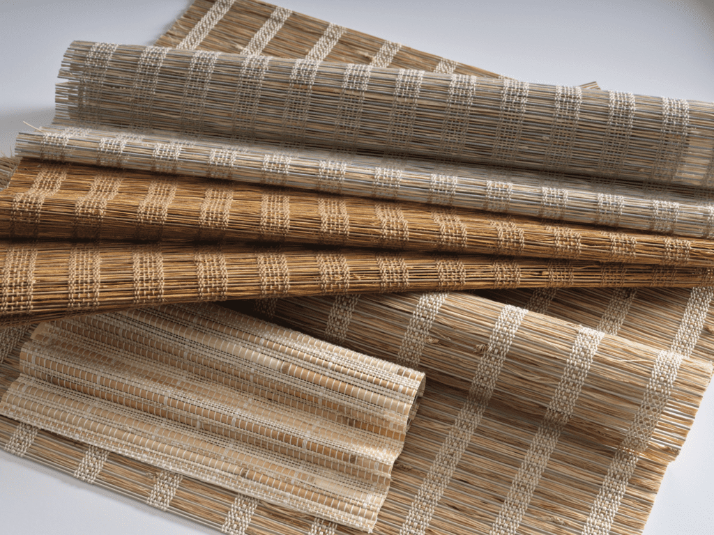 Several rolled and layered woven straw mats with white thread accents are arranged on a flat surface.